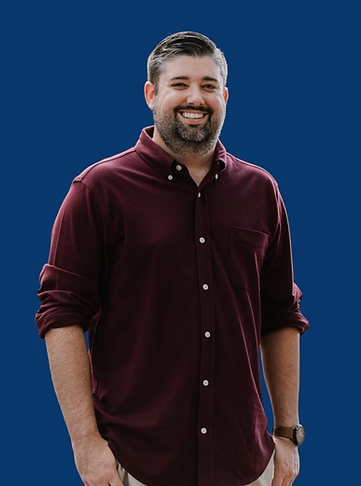 Smiling man wearing a maroon shirt on a blue background, portrait shot