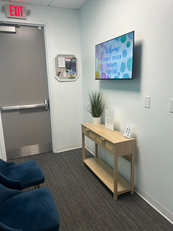 Waiting room with TV, Welcome to the office, blue chairs and a console table.