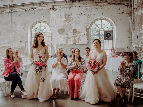 A lesbian/trans wedding couple during their processional at their Barbie-inspired wedding. Ein lesbisches/trans Hochzeitspaar während ihres Einzugs bei ihrer Barbie-inspirierten Hochzeit.