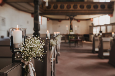 Ansicht der leeren Kirche, die Kirchenbänke sind mit Blumen und Kerzen dekoriert für die Hochzeit geplant von Hochzeitsplanerin Hessen. // View of the empty church, the pews are decorated with flowers and candles for wedding planned by wedding planner Hesse.