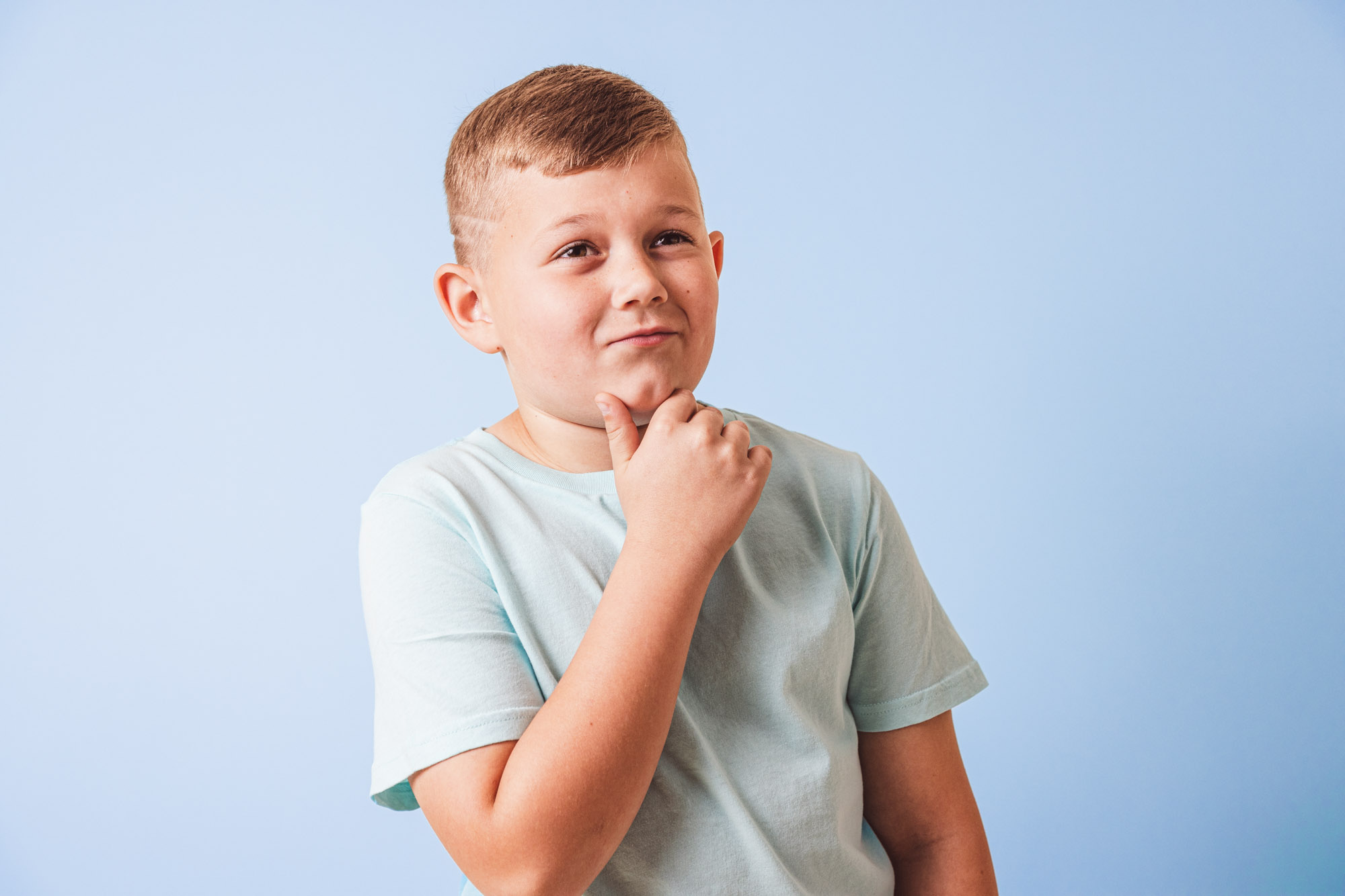 Pediatric patient making a thoughtful expression in front of blue wall