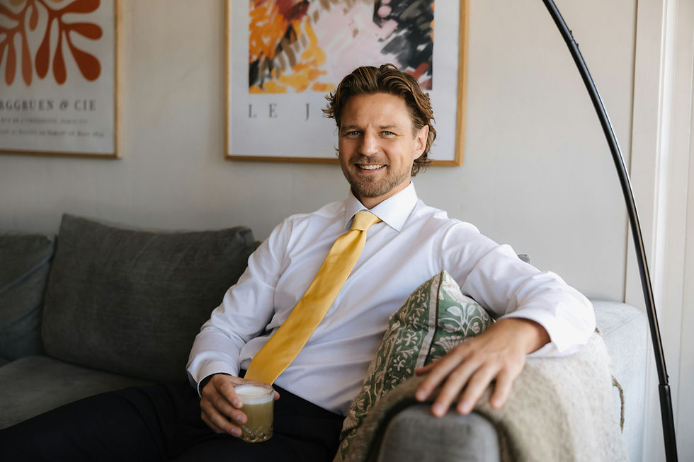Businessman smiling on a sofa in a modern office, representing confident workplace communication.