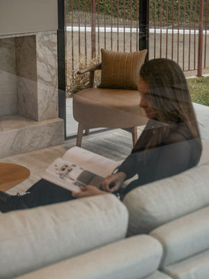 Soft neutral home interior with a woman reading quietly, representing intentional living, nervous system support, and emotional reclamation.