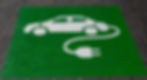 a green and white ev charging sign on the pavement