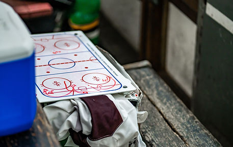 Hockey coach's rink diagram with plays drawn in red marker besides hockey gear
