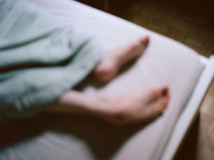 Feet resting on a bed.