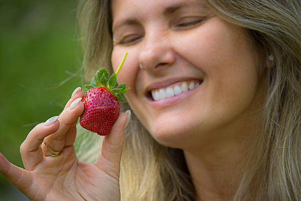 Smiling woman eating a low FODMAP strawberry