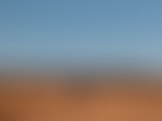 Un SUV et une personne se tiennent sur des dunes de sable orange sous un ciel bleu, dans un désert paisible.