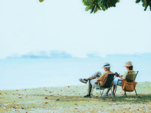 Husband and wife sitting on deck chairs looking out to sea