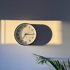 A wall clock is illuminated by early morning sunlight