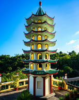 Multi-tiered pagoda with green and red roofs at the Taoist Temple in Cebu, surrounded by greenery.