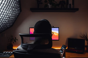 A man sitting in the dark behind a computer scrolling through dating apps.
