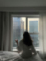A hotel guest in a robe taking in a city skyline at sunset