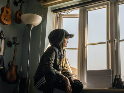 jeune adolescent pensif regardant par la fenêtre, évoquant l'isolement et le mal-être 