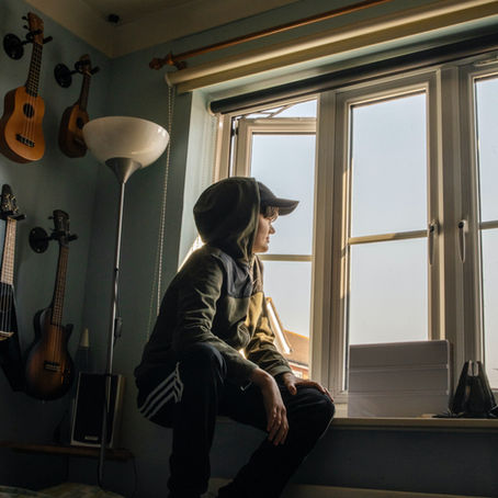 jeune adolescent pensif regardant par la fenêtre, évoquant l'isolement et le mal-être