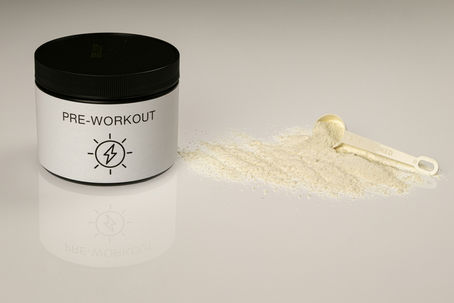 Pot pre-workout met poeder en maatschepje als supplement voor extra energie en focus tijdens krachttraining.