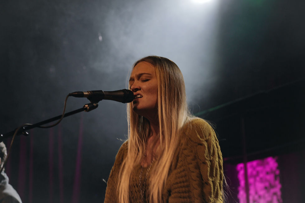 Female singer performing under stage lights, expressing vocal emotion and technique