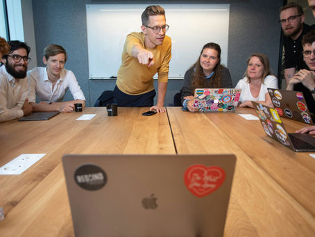 team at a board room table with a laptop and a man pointing at the laptop