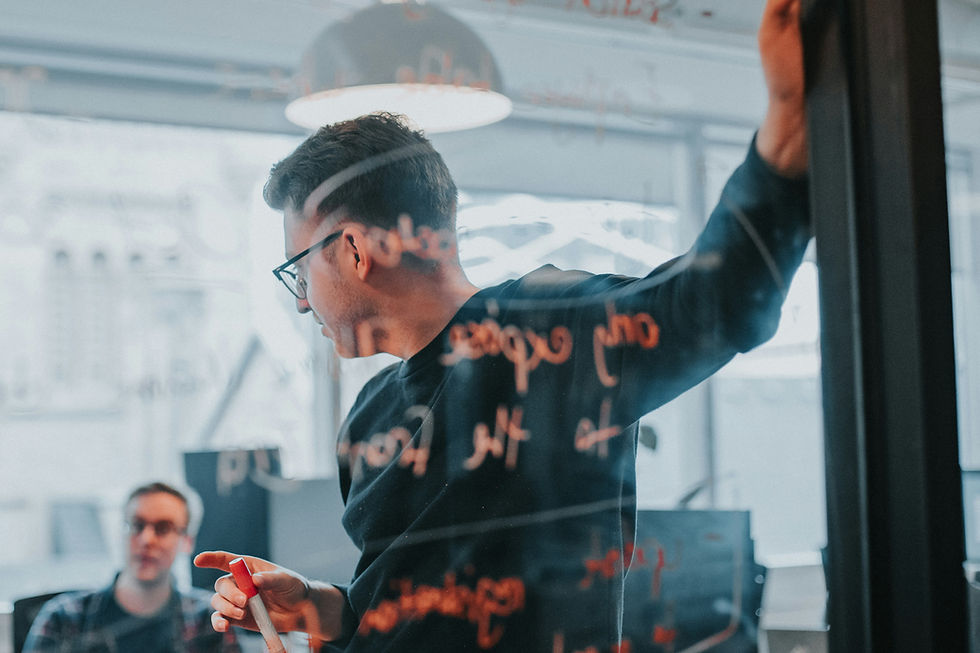 Man writing on glass wall during office meeting
