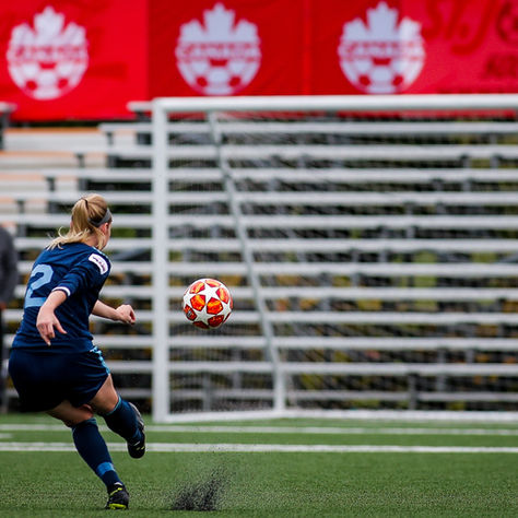 Female football player practicing first-time shooting technique - support for this and other football coaching needs available in Bournemouth & Poole.