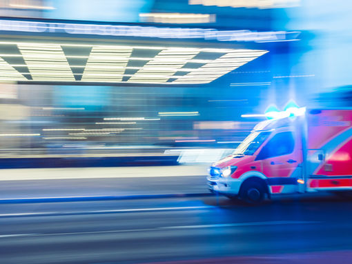 Ambulance speeding down a road, symbolizing the urgency of unexpected emergencies and the importance of having an emergency fund for financial preparedness.