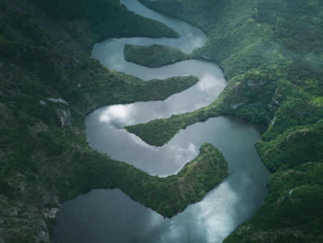 Slingerende rivier als symbool voor vertragen, aanwezigheid en het loslaten van een vast einddoel.