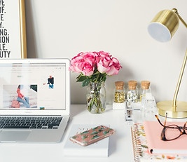 Health coach desk with flowers, laptop, glasses, and a sign.