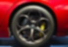 Red car wheel and tire detail, with a gray rim and yellow brake calipers.