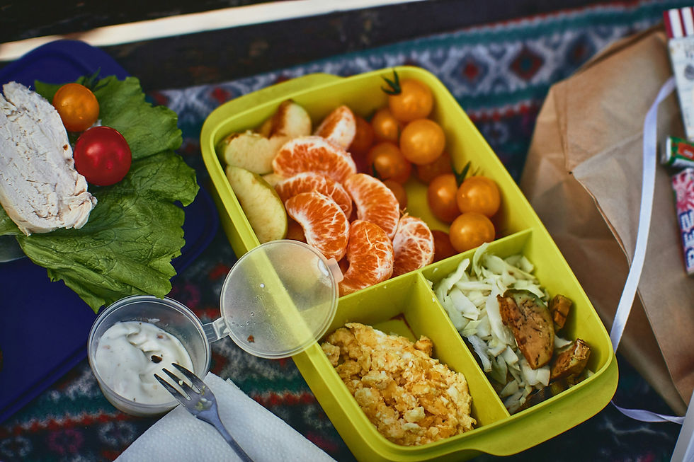 A vibrant lunch box meal featuring fresh mandarin slices, cherry tomatoes, chopped cabbage with grilled vegetables, and creamy scrambled eggs, served with a side of lettuce, cherry tomatoes, and a dollop of creamy dressing.