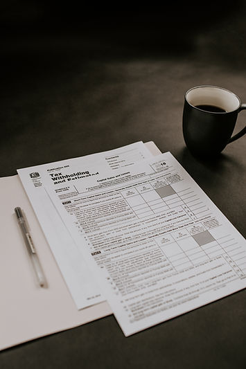 a cup of coffee, tax prep paperwork, pen, dark background