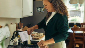 Woman preparing a protein-rich breakfast in a warm, sunlit kitchen, representing a practical strategy for managing perimenopause sugar cravings.