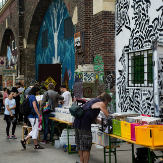Tourists exploring street art and book stalls on a Tel Aviv graffiti tour.
