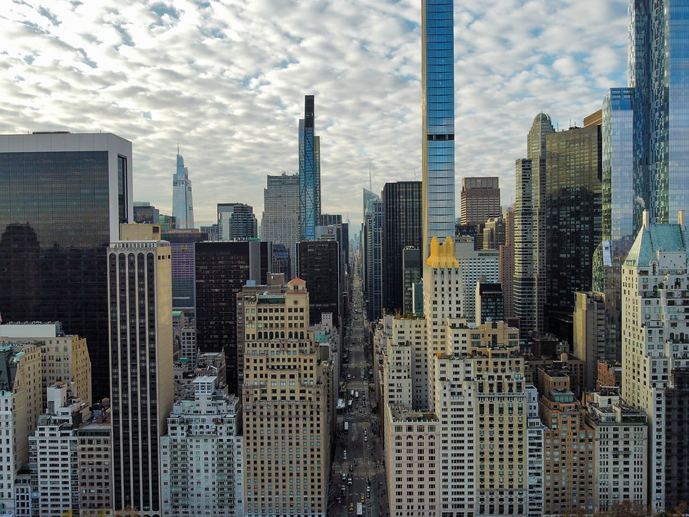Aerial view of Midtown Manhattan with high-rise buildings and city streets beneath a dramatic sky.
