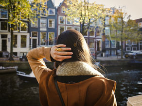 Young woman standing by an Amsterdam canal, reflecting — finding an English-speaking psychologist in Amsterdam for anxiety and therapy support