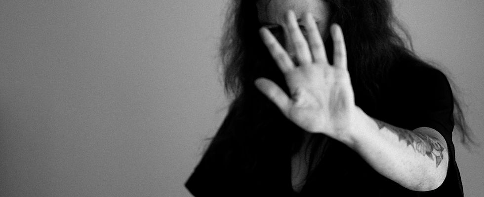 Black and white photo of man looking down and holding tatooed arm up with hand covering face. Image by Annie Spratt