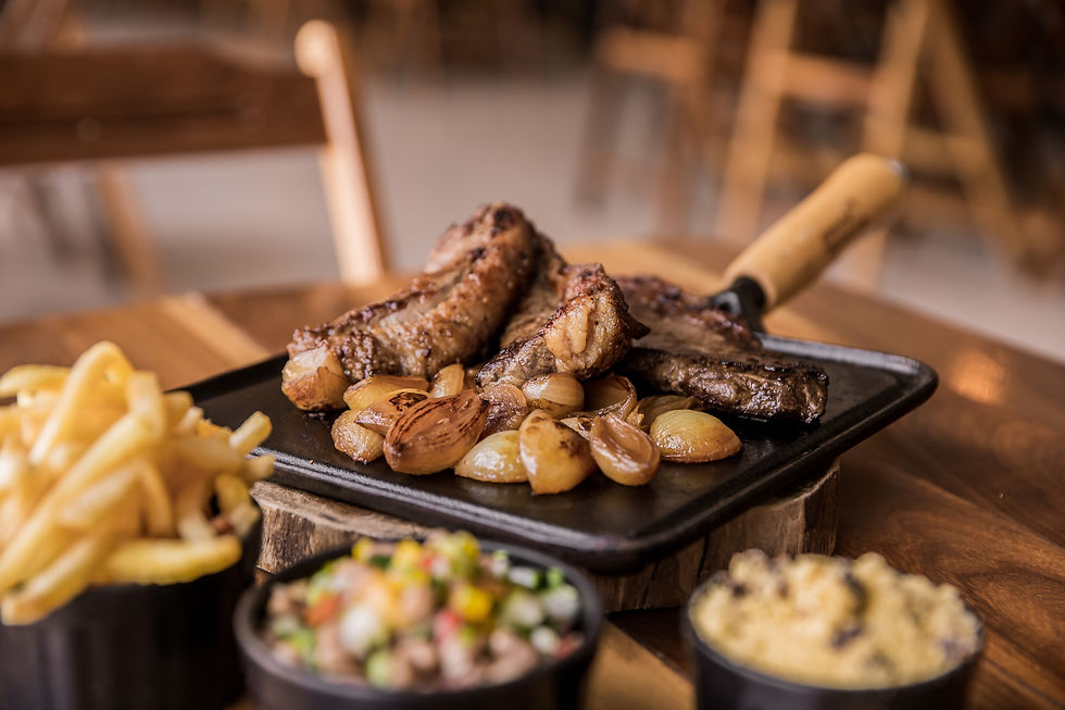 Grilled meat and onions on a tray with fries, salsa, and corn sides on a wooden table in a cozy setting. Warm, inviting tones.