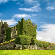 The ruins of BallyCarbery castel with blue sky and white clouds