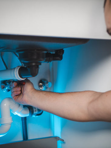 Plumber working on kitchen water and plumbing services during a renovation