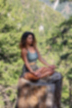 A woman meditating on a tree stump.
