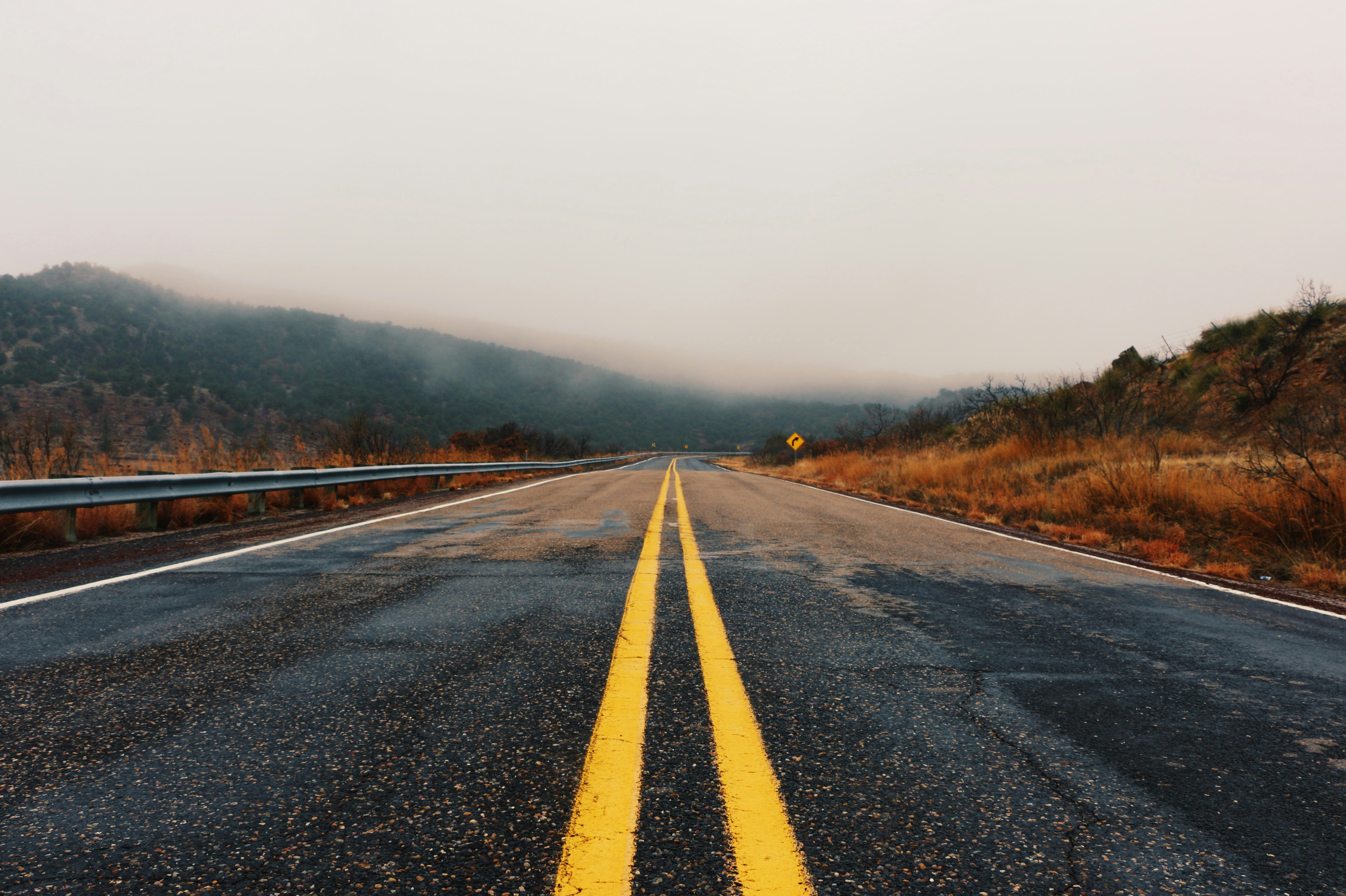 Winding two-lane road through autumn forest with yellow center lines