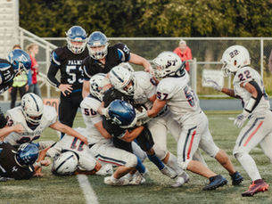 Youth football players gang tackling a ball carrier at the line of scrimmage during a game in Northern Virginia