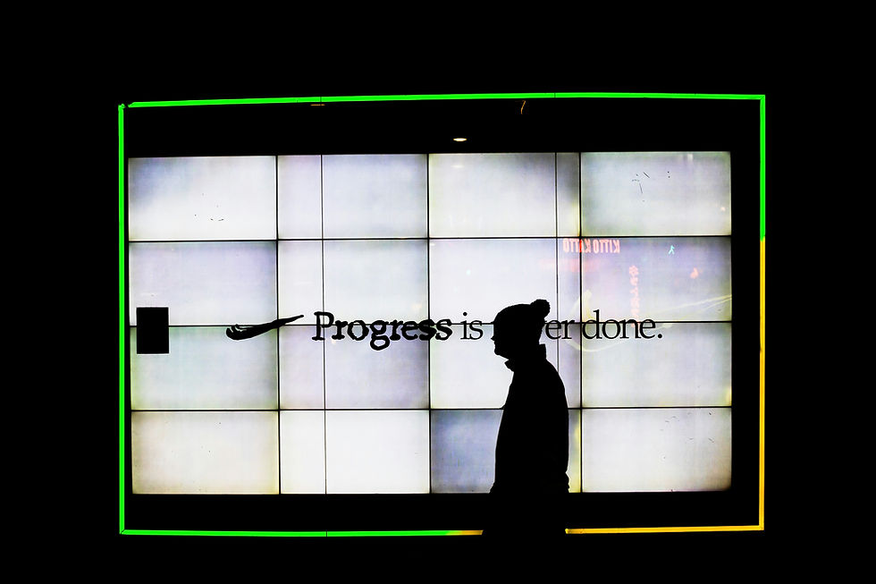 Silhouetted figure standing before a large illuminated wall display with the words “Progress is never done,” suggesting ongoing change and the unfinished future of work.