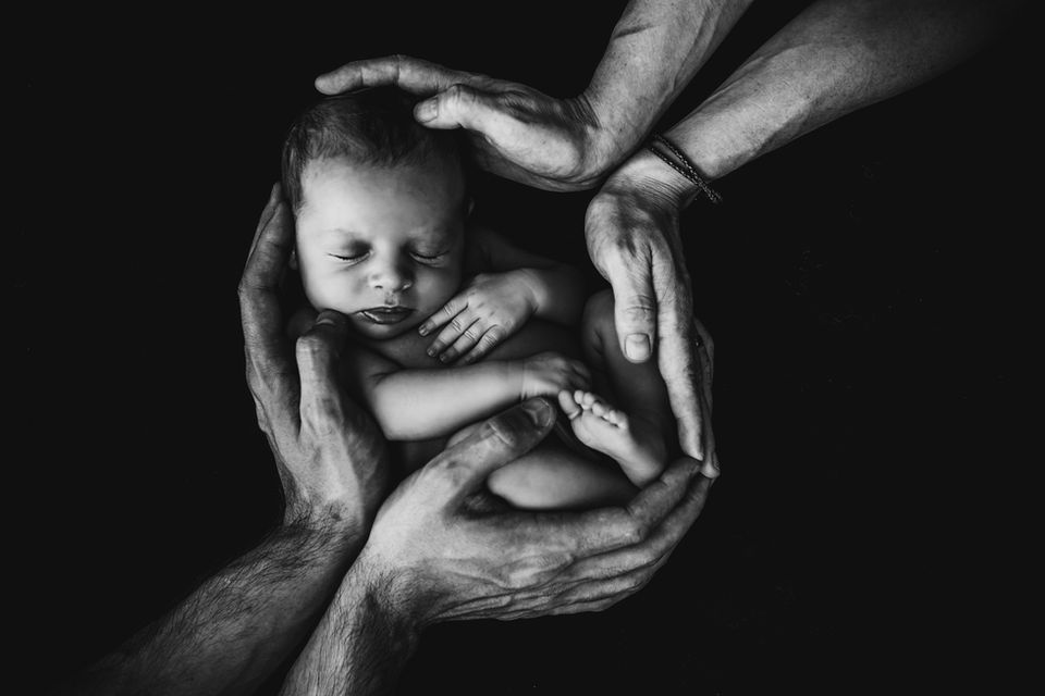 Newborn Photography by Blake Ferguson depicts a Monochrome Image of a Baby being held by Parents in Ontario, Canada.
