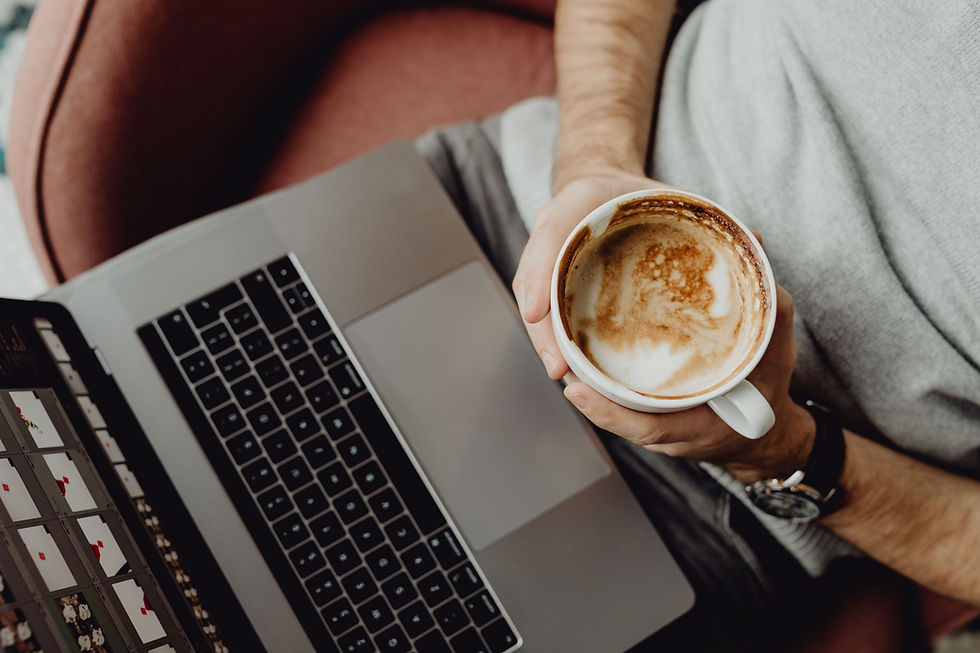 man holding a cup of coffee in front of a laptop