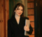 Femme souriante en costume noir tenant un ordinateur portable