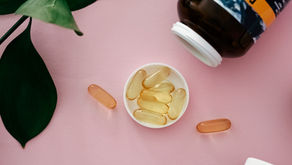 Pills spill from an open bottle labeled "FORD" on a pink surface, surrounded by green leaves. Clear and amber capsules are visible.