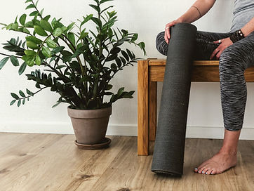 pflanze im zimmer neben frau mit yogamatte