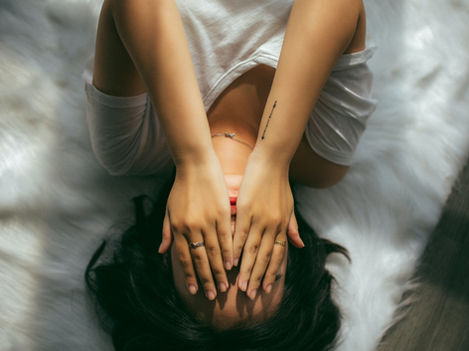 A girl laying with her hands over her eyes