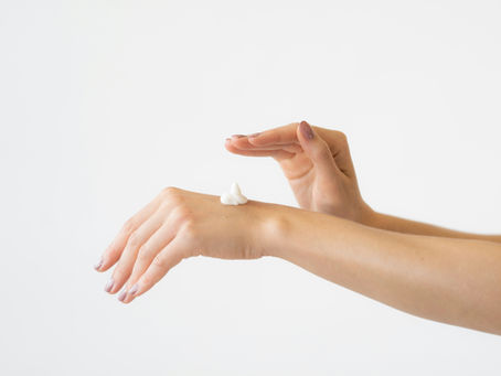 A woman in her 40s gently applies moisturizer to her forearm in warm morning light — illustrating perimenopause skin care and barrier repair - from Vibrance Way