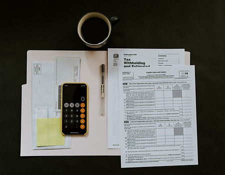 Tax preparation and financial planning workspace featuring IRS tax forms, calculator, and coffee, representing tax-efficient financial planning, wealth management, and accounting strategies discussed by Wolfpack Wealth Management and Wolfpack Tax & Accounting on the Catholic Money Mastermind Podcast.